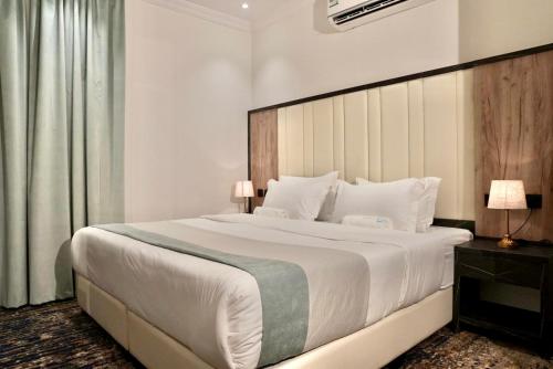 um quarto com uma grande cama branca e uma grande cabeceira de cama. em لحظات الفندقية حراء em Jeddah