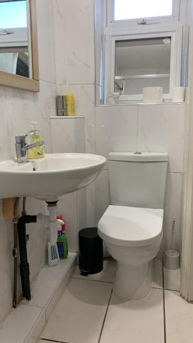 a white bathroom with a toilet and a sink at R J Apartment in London
