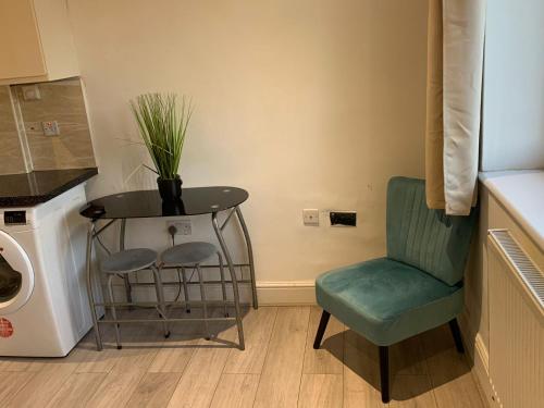 a laundry room with a table and a green chair at R J Apartment in London