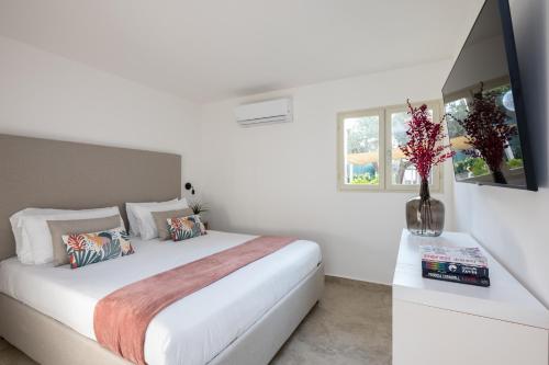 a white bedroom with a bed and a vase with flowers at Sopramare Resort in Piano di Sorrento