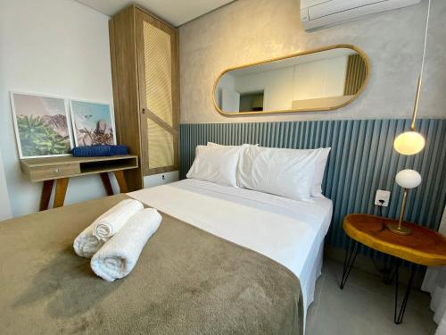 a bedroom with a large white bed with a mirror at Green Porto 103 Flat novíssimo no centro de Porto in Porto De Galinhas