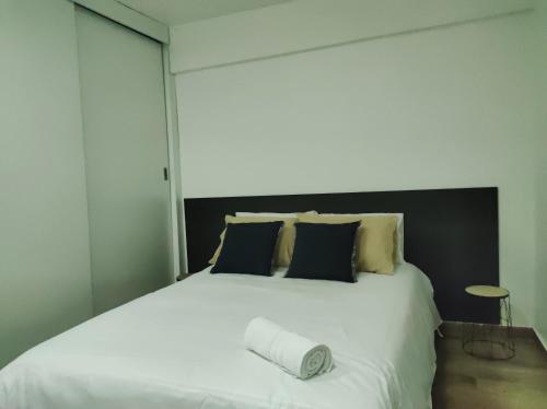 een slaapkamer met een groot wit bed met kussens bij Hermoso departamento piso 1 in Loja