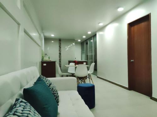 een woonkamer met een witte bank en een tafel bij Hermoso departamento piso 1 in Loja