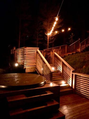 a wooden deck with stairs and lights at night at Tretoppen - Ny moderne hytte, Unike Finnskogen in Torsby