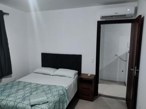 ein Schlafzimmer mit einem Bett und einer Tür zu einem Bad in der Unterkunft Hotel Morro do campo in Antônio Carlos