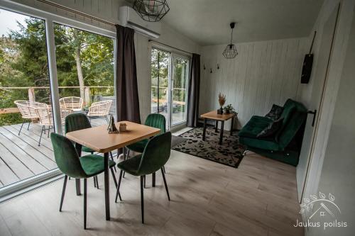 a living room with a table and chairs and a balcony at Jaukus poilsis in Mažonai