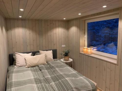 a bedroom with a large bed with a window at Tretoppen - Ny moderne hytte, Unike Finnskogen in Torsby