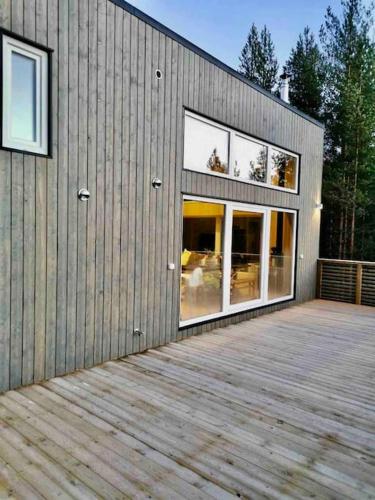 a building with a wooden deck with windows on it at Tretoppen - Ny moderne hytte, Unike Finnskogen in Torsby