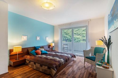 バーデン・バーデンにあるFerienwohnung Am Paradiesの青い壁のベッドルーム1室、ベッド1台、窓が備わります。