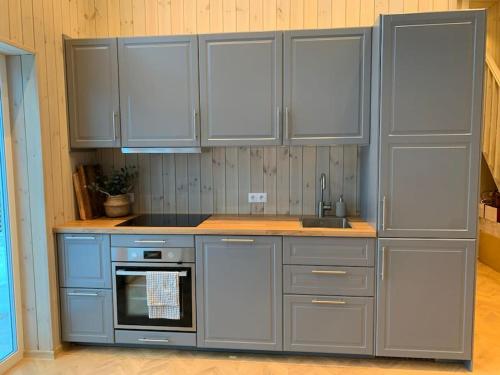 a kitchen with gray cabinets and a sink at Tretoppen - Ny moderne hytte, Unike Finnskogen in Torsby