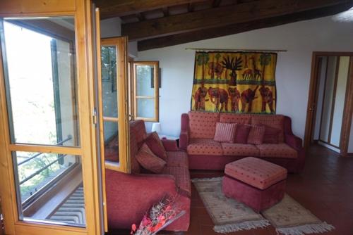 a living room with a red couch and a window at Casa Tre Pini in Serravalle Pistoiese