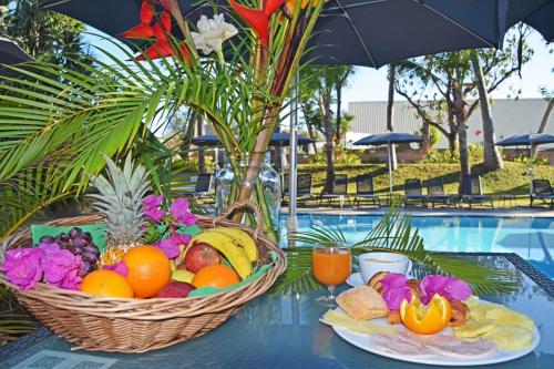 two baskets of fruit on a table next to a pool at Hotel Exsel Alamanda in Saint-Gilles-les-Bains