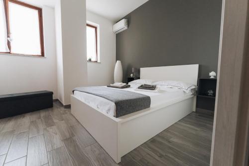 una camera bianca con un letto bianco e due finestre di Grey's Apartment a Catania