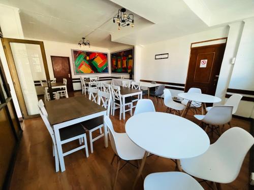 uma sala de jantar com mesas e cadeiras brancas em Nómada Hostel Osorno em Osorno
