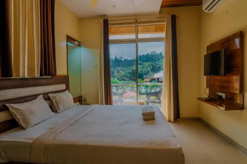 a bedroom with a large bed with a large window at oakwood mahabaleshwar in Mahabaleshwar