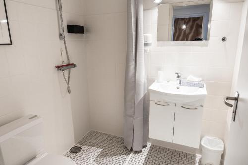 a white bathroom with a sink and a shower at Hotel Herning in Herning