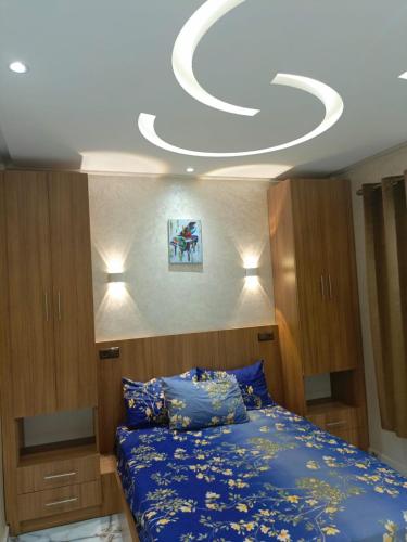 um quarto com uma cama azul e um tecto branco em Aourir's new appartement em Agadir
