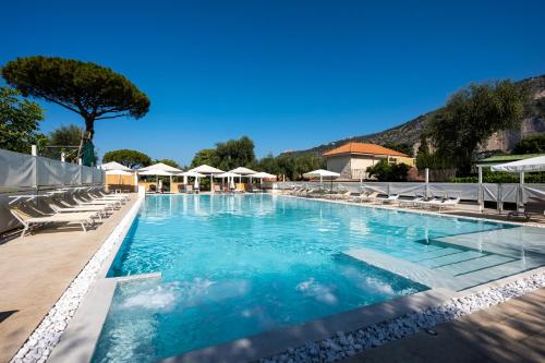 une grande piscine avec des chaises longues et des parasols dans l'établissement Sopramare Resort, à Piano di Sorrento