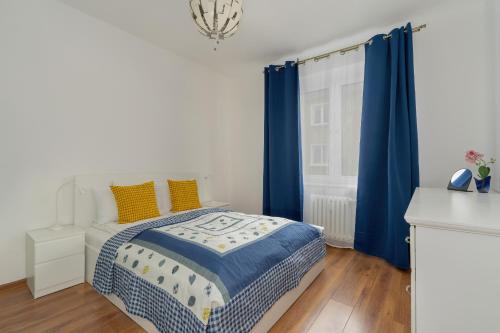 1 dormitorio con 1 cama con cortinas azules y ventana en Traditionally Furnished Apartment with Balcony in Poznan by Renters en Poznan
