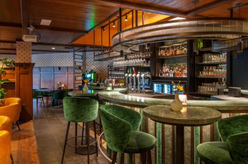 a bar with green chairs and tables in a restaurant at Van der Valk Hotel Hengelo in Hengelo