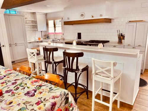 eine Küche mit weißen Schränken und einer Theke mit Stühlen in der Unterkunft Los Respigos de la Pradera in Ampuero