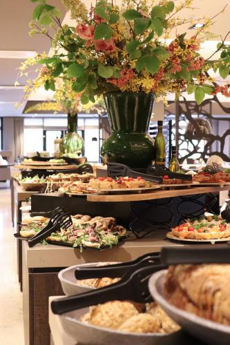a buffet line with many plates of food and flowers at Van der Valk Hotel Hengelo in Hengelo