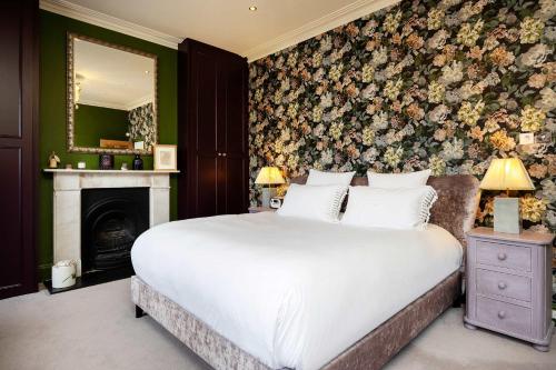 a bedroom with a large bed and a fireplace at Veeve - Golds and Greens in London