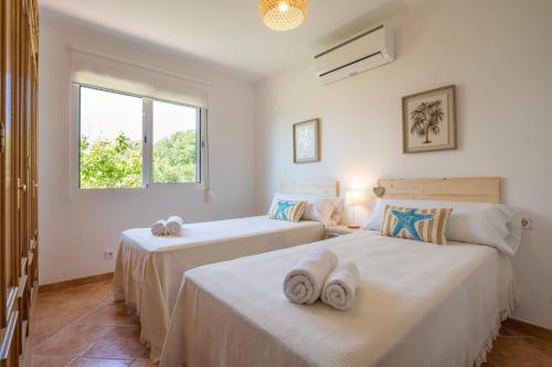 two beds in a room with a window at Villa Pepe by Villa Plus in Es Mercadal