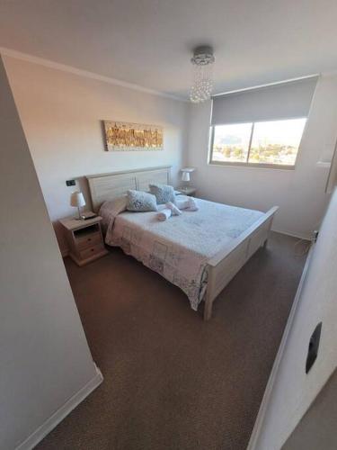 a bedroom with a large bed and a window at Dpto Cerca de Strip Center Oasis in Calama