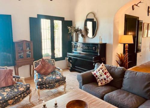 a living room with a couch and a piano at Villa Lavanda by Época Suites in El Castillo de las Guardas