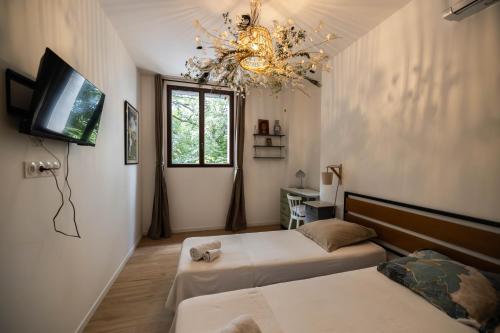 1 dormitorio con 2 camas, TV y lámpara de araña en Gîtes du Castell de Blés, en Saint-Génis