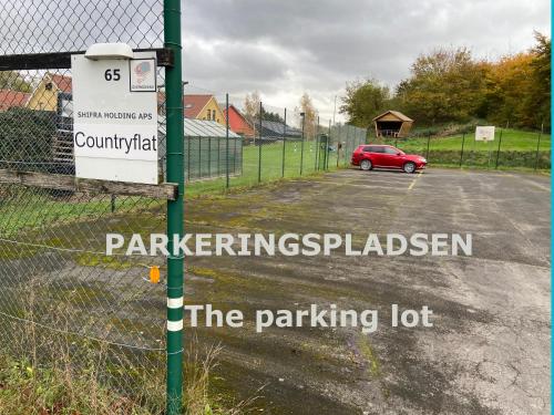 a parking lot with a red car parked in a parking lot at Country flat in Roskilde
