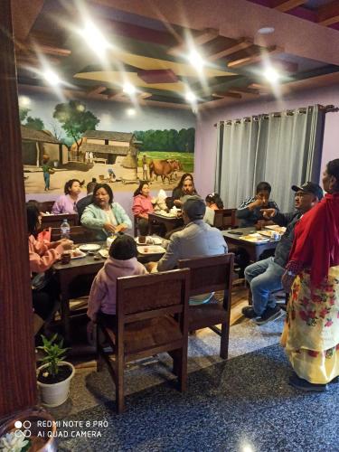 a group of people sitting at tables in a room at Hotel Namo Buddha in Sauraha