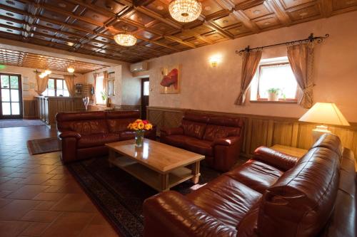 a living room with leather couches and a table at Hotel Karpatsky Dvor Lozorno in Lozorno