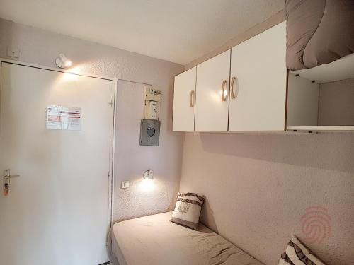Habitación pequeña con cama y armarios blancos. en Studio Lamalou-les-Bains, 1 pièce, 2 personnes - FR-1-451-62 en Lamalou-les-Bains