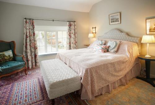 a bedroom with a bed and a chair and a window at Chanting Hill Farmhouse at Castle Howard in Welburn