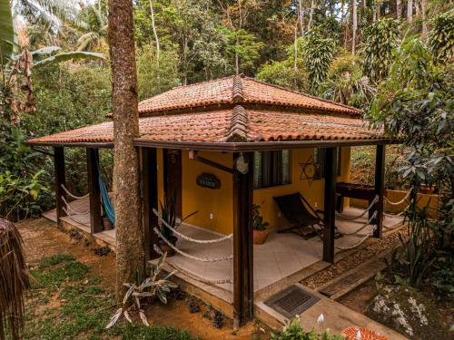 a small yellow house in the middle of a forest at Espaço Viverde Penedo in Penedo