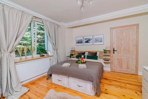 a bedroom with a large bed and a window at Apartamenty Colobrzeg Sweet Home in Kołobrzeg