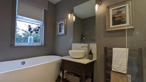 a bathroom with a tub and a sink and a window at The Posting House in Kilchrenan