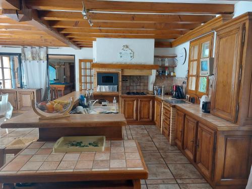 une grande cuisine avec des placards en bois et un évier dans l'établissement GITE LA LAUZERAIE, à La Bourboule