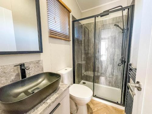 La salle de bains est pourvue d'un lavabo, de toilettes et d'une douche. dans l'établissement Stunning Lodge With Decking Nearby Hunstanton Beach, Sleeps 6 Ref 23215k, à Hunstanton