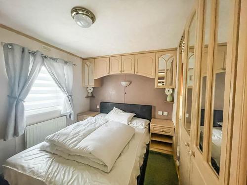 a bedroom with a white bed and a window at Lovely Caravan With Large Decking At Southview Holiday Park Ref 33108s in Skegness