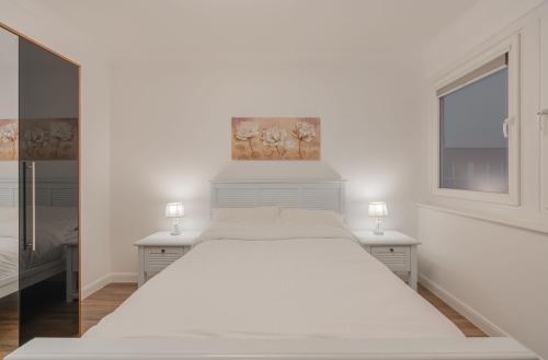 a white bedroom with a large white bed with two tables at Beachfront Penthouse , Roof Balcony With Sea View, Free Use of Hotel's Spa, Sauna, Gym and Pool in Brighton & Hove
