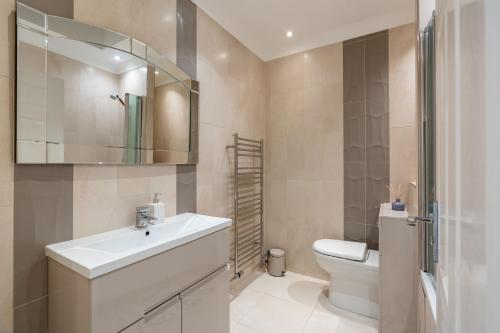 a bathroom with a sink and a toilet and a mirror at Beachfront Penthouse , Roof Balcony With Sea View, Free Use of Hotel's Spa, Sauna, Gym and Pool in Brighton & Hove