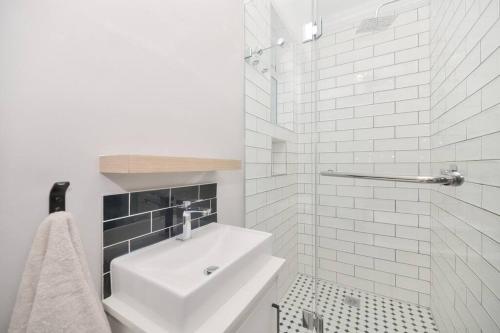 ein weißes Bad mit einem Waschbecken und einer Dusche in der Unterkunft Alwil Ocean View Villas - Unit 5 in Struisbaai