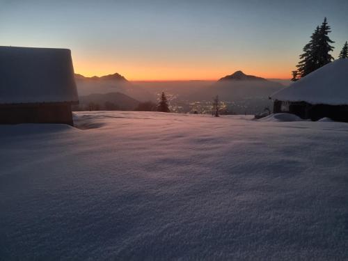 a snow covered roof with the sunset in the background at Chalet de la Joux in Saint-Sigismond