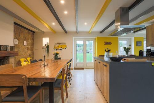 a kitchen with a wooden table and a dining room at Le clos du Verdelet vue mer piscine in Planguenoual