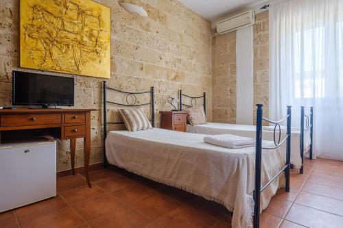 1 Schlafzimmer mit 2 Betten, einem Schreibtisch und einem TV in der Unterkunft Tenuta San Trifone Corbezzolo in Seclì