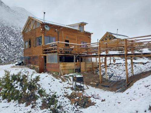 una cabaña de madera en la nieve con nieve en Rincón Trasandino en Potrerillos