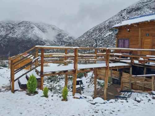 una cabaña en la nieve con montañas en el fondo en Rincón Trasandino en Potrerillos